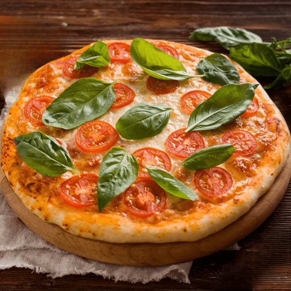 Valley Pizza's Margherita pizza with fresh basil leaves and sliced tomatoes on a wooden board.