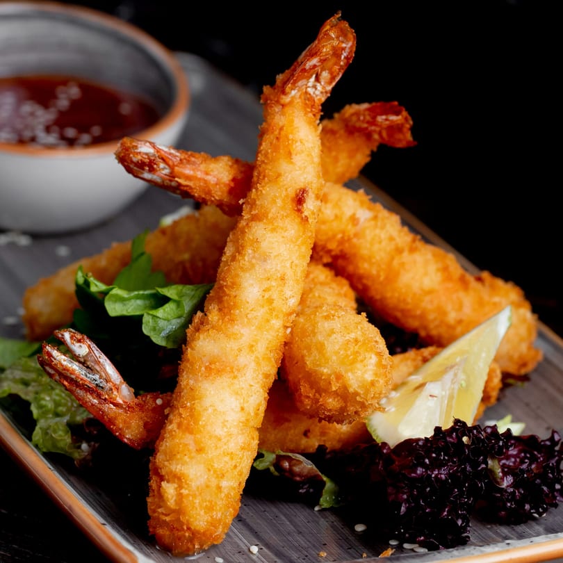 Crispy fried shrimp tempura with lettuce, lemon, and a side of dipping sauce.